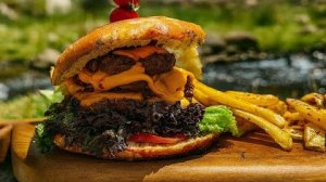 Бургер с сочными слоями, сыром, картофелем фри и карамелизированным луком.