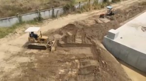 Бульдозер засыпает огромную дренажную канаву.