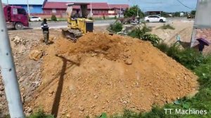 Соединение дороги с мостом: множество самосвалов выгружает камень, а бульдозер его толкает.