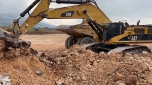 Экскаватор Cat 385C загружает щебень на самосвалы Cat 777C