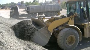 Погрузчик Cat 962G грузит щебень в тонары