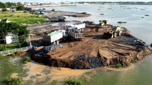 Оползень при отсыпке берега. Бульдозер толкает камни и песок.