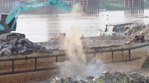 Экскаватор создает защитное укрепление от оползней и укрепляет берег.