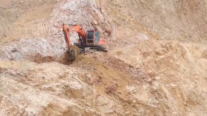 Экскаватор DOOSAN DX220LCA копает каменистый грунт на горе.