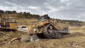 Бульдозер Cat D8R рыхлит плотные слои скальной породы, чтобы помочь экскаватору Cat 385C.