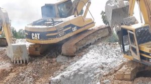 Экскаватор, с помощью коллег, выбирается из грязевого канала.