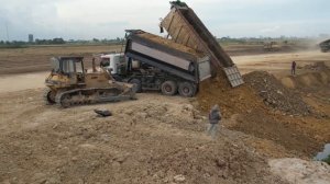 Komatsu D58 и грузовики отсыпают берег озера.