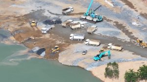 Бульдозер Shantui перемещает песок и щебень, 25-тонные грузовики разгружают.