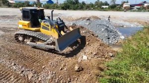 Успешная операция по превращению озера в сушу | Бульдозер, толкающий камни, и самосвал, разгружающий