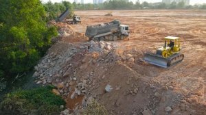 Строительство полигона для захоронения отходов. Самосвалы перевозят грунт, бульдозер толкает грунт.