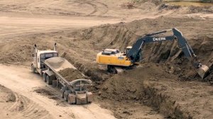 Огромный экскаватор безостановочно копает и загружает самосвалы в 4k