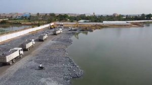 Мы показываем технику засыпки камня в огромное озеро, используя самосвал для перемещения камня и бул