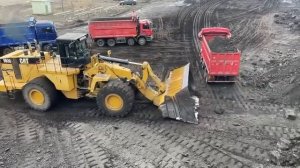 Огромный колесный погрузчик Caterpillar 992G Загружает уголь на грузовики -