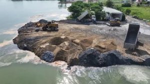 Super Wheel Loader строит новую дорогу на озере, сбрасывая грунт в воду.