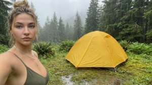 Девушка идёт в лес в дождливую погоду ,чтобы установить палатку и отдохнуть от городской суеты.