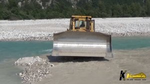 Бульдозер Caterpillar D9N копает гравий в воде.