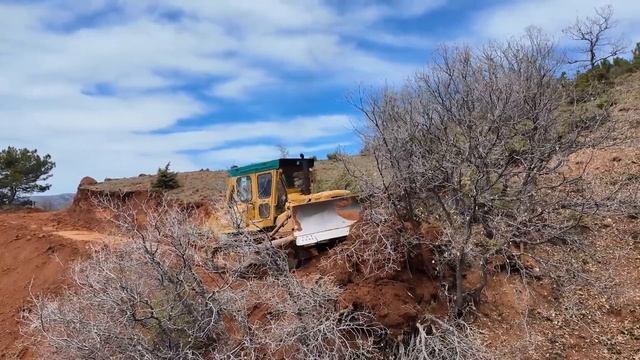 CAT D7 работает делает дорогу на каменистой местности. смотреть онлайн