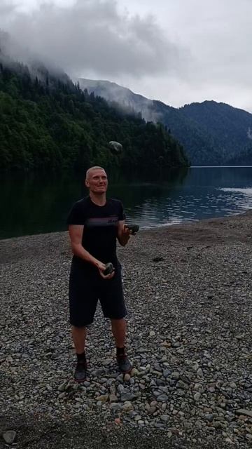 Дядя Вася жонглирует булыжниками на берегу озера Рица, июль 2025 г.