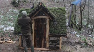 Парень в одиночестве строит каменный дом на берегу реки в лесу. ушкрафт