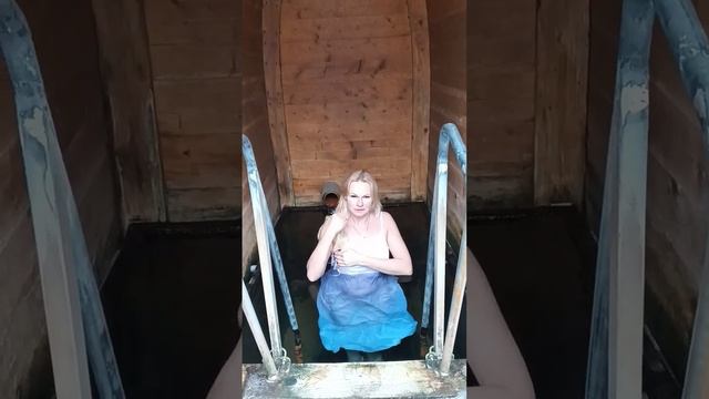 Красивая девушка в сорочке купается в ледяной воде. Моржевание и зимнее плавание.