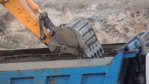 Аккуратный экскаваторщик грузит Самосвал Глыбами.