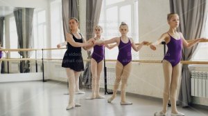 Adorable little girls in bright bodysuits are having classical ballet lesson learning leg movements
