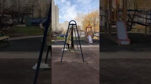 Женщина выбивает ковёр на детской площадке