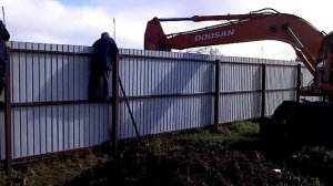 эсковатор капает через забор