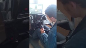 Ученик на тренажере в Автошколе. Экзамен ГАИ. Город