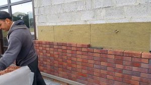Процесс облицовки дома кирпичом.