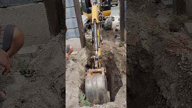 мини эксковатор копает траншею для водопровода
