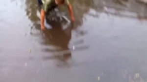 Мальчик купаеться в луже