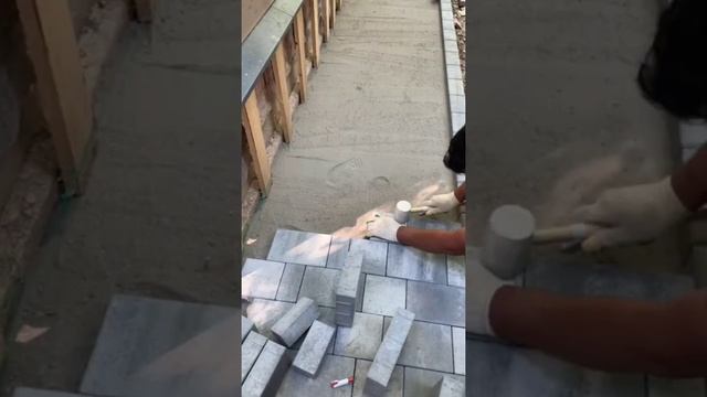Мощение отмостки вокруг дома тротуарной плиткой.