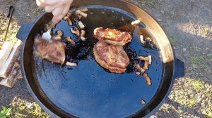 Жареная картошка с мясом на большой сковороде на огне.