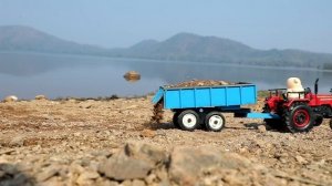 Желтый экскаватор грузит песок и засыпает яму