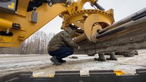 Автогрейдер борется со льдом на дороге.