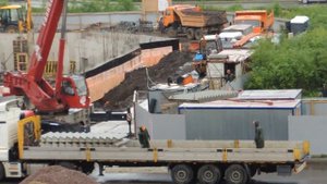 Автокран разгружает Грузовик с полуприцепом