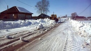Трактор К-700 гребёт снег по улице весной