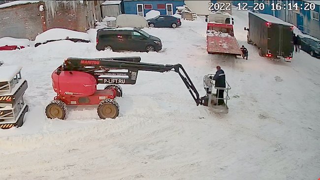 Коленчатый дизельный подъемник Manitou 200ATJ съезжает с эвакуатора зимой
