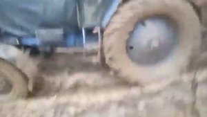 МТЗ 82 тянет груженный дровами прицеп по грязи.