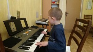 Уникальный мальчик на синтезаторе играет и поет песню.