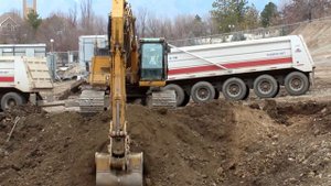 CAT 345C Excavator loading a double dump truck on a large construction site