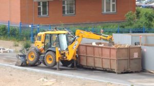 Экскаватор-погрузчик утрамбовывает Пухтовоз и загружает в него мусор даже в сильный дождь.