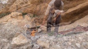 Camping alone in a rock hole in a spooky canyon. Wooden cooking tongs. Meatballs on bread and stone