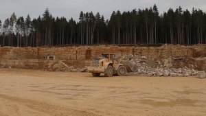Погрузка камней в карьере. Грязь. Большие погрузчики.