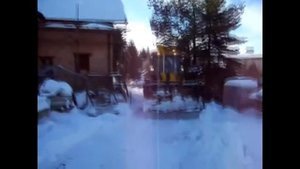 Универсальный экскаватор погрузчик JCB 4CX убирает во дворе жилого дома снег