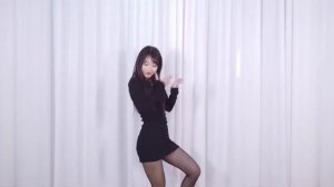 Девушка танцует в черном облегающем платье, в черных колготках и туфлях на шпильке.