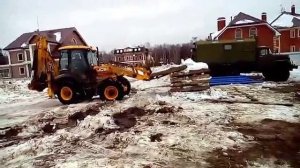 Экскаватор-погрузчик перевозит плиты