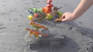 Игрушки динозавры на море. Динозавры игрушки строят машинку из песка.