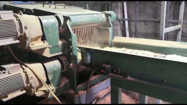 Скребковый транспортер в паре с рубительной машиной в работе на производстве